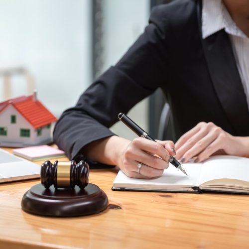 Close-up of a woman lawyer holding a pen with a notebook at the office.